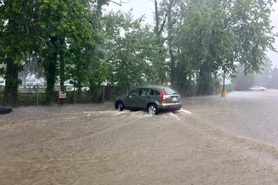 A sports utility vehicle drives throw brown floodwaters that have inundated the entire area depicted in the picture.